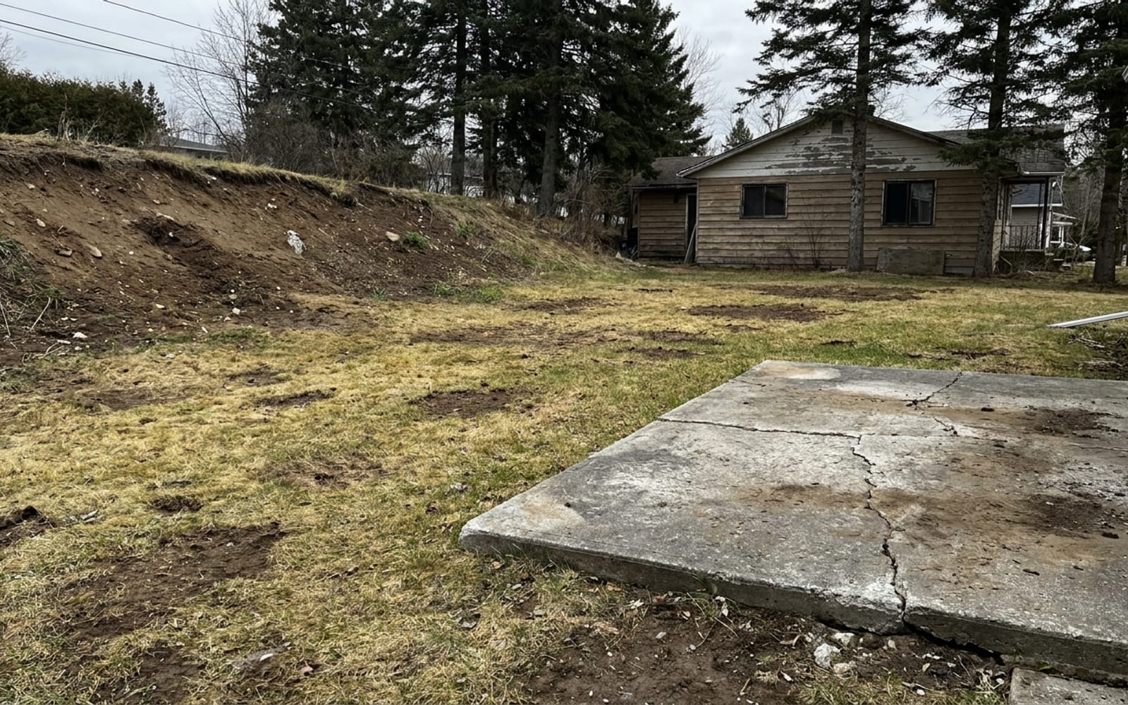 Avant: pelouse irrégulière, talus dénudé, dalle de béton vieillie